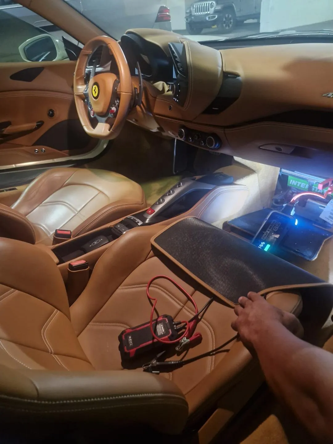 Batería accesible en el espacio para los pies del pasajero de un Ferrari, con equipo de servicio cerca