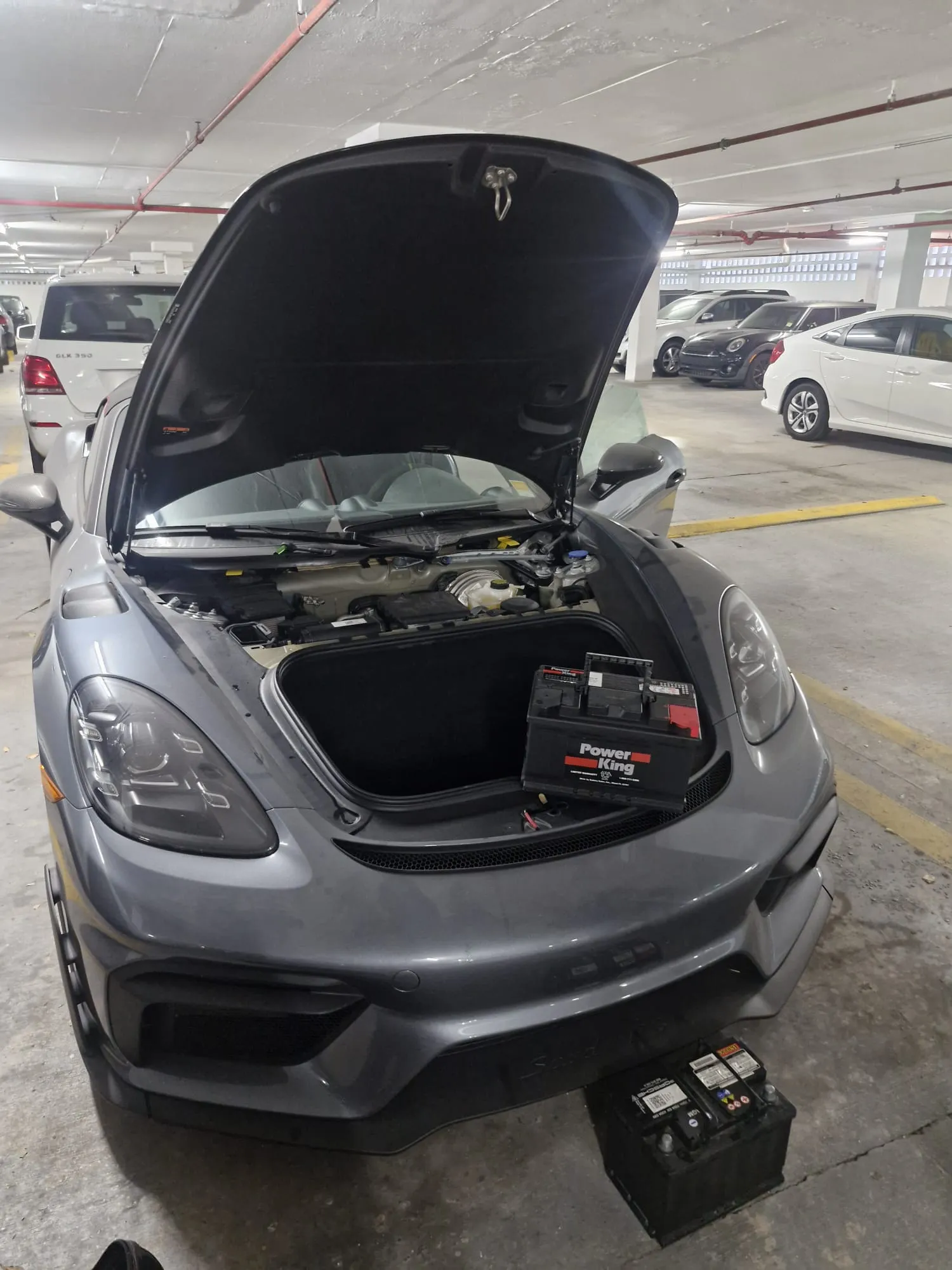 Porsche con el capó delantero abierto y equipo para servicio de batería